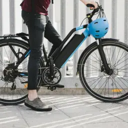 Człowiek na rowerze elektrycznym z niebieskim kaskiem. Zastanawiasz się, ile kosztuje rower elektryczny?